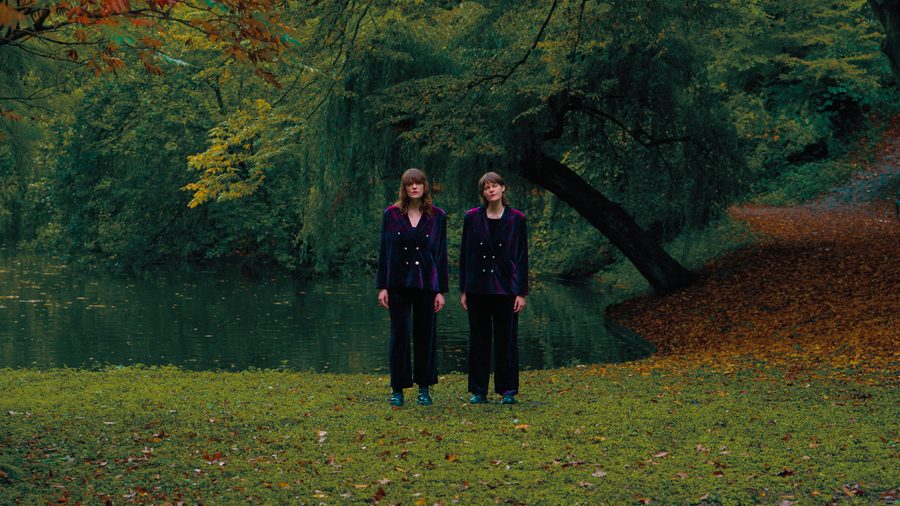 Is it really you I’m missing?: two people in velvet suits standing by a pond in autumn