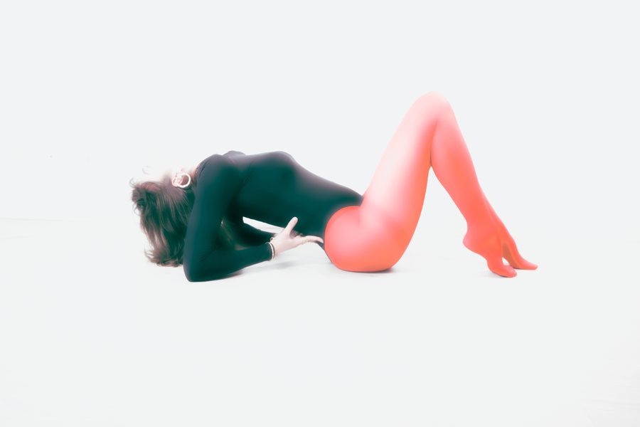 Noor: a dancer in a black bodysuit and coral tights lying on a white floor